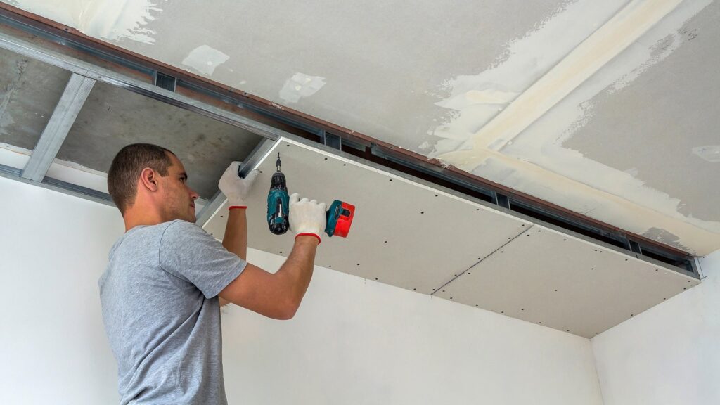 Operaio che fissa una lastra di cartongesso al soffitto per mezzo di appositi sostegni